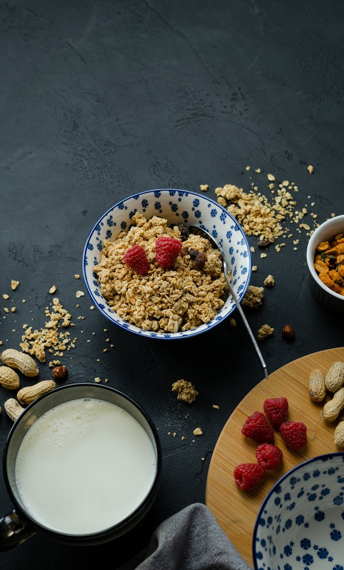 Top view of granola with raspberries and milk on a dark surface, perfect for a healthy breakfast setup.